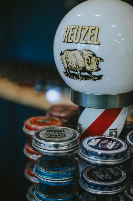 Barber pole and rows of pomade tins on the counter at HiT Barbershop